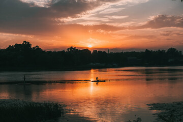 Silhouette image of a young girl on stand up paddle board in a river before sunset. Sup surfing