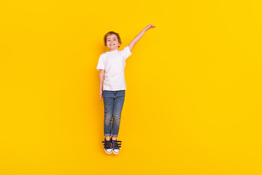 Full length body size view of handsome cheerful funny pre-teen boy jumping measuring copy space isolated over vivid yellow color background