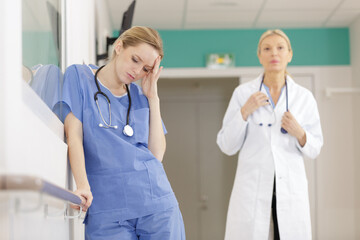 female nurse with a headache resting in hospital corridor - Powered by Adobe