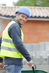 a happy builder carrying a barrow outdoors