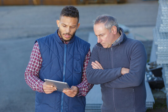 two workmen outdoors looking at digital tablet