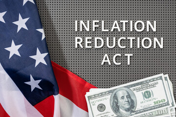 Inflation reduction Act law concept. Fat lay of text, american flag and dollar banknotes