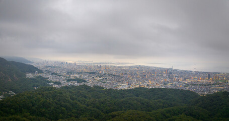 Low fog over sprawling city between forested mountains and bay at dawn