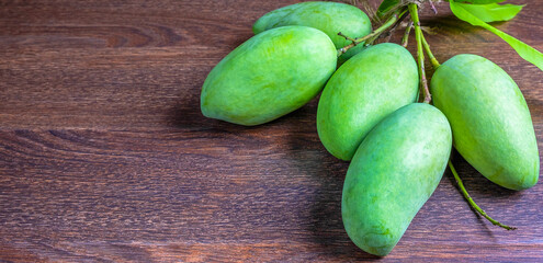 Fresh green mango and green leaf in the basket ,Group of raw mangoes organic on brown wooden backgroundv