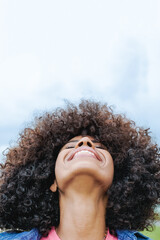 Happy african american young woman looking up with sky on background - Focus on mouth