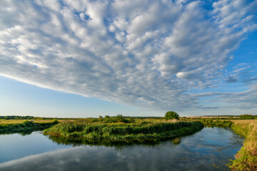 Panoramic view landscape with bending river and floating clouds at sunset. Wide angle view.