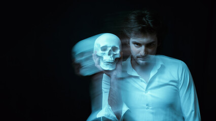 portrait of psychopathic man with mental disorders with a human skull in his hand