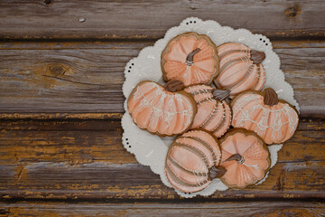 Pumpkin shaped cookies with royal icing on white plate and wooden table, copy space