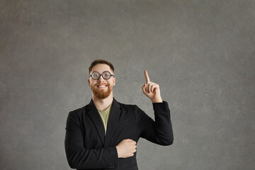 Smart excited businessman wearing funny thick lens round glasses and suit raising finger having idea understanding something important, looking confident and inspired. Studio half-length portrait