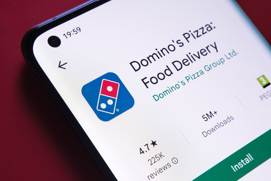dominos Pizza app seen in Google Play Store on the smartphone screen placed on red background. Close up photo with selective focus. Stafford, United Kingdom, August 2, 2022.