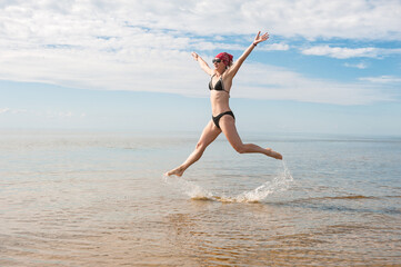 Obraz premium Happy funny woman jumping in the water of sea