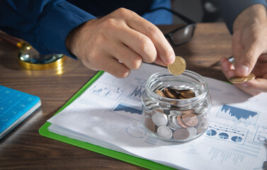 Businessman putting coin in glass bank. Saving money