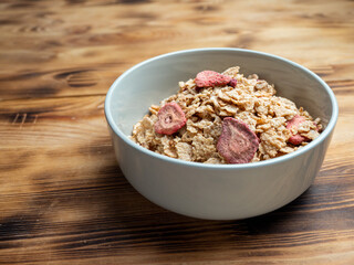 A cup with muesli and fresh berries on a wooden table. Healthy food, snack or breakfast.