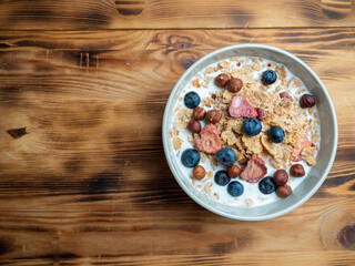 A cup with muesli and fresh berries on a wooden table. Healthy food, snack or breakfast.