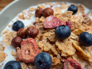 A cup with muesli and fresh berries on a wooden table. Healthy food, snack or breakfast.