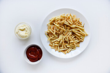 Delicious potato chips straws on a white saucer with sauce. Fast food with fried potato sauce straws.