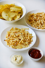 Delicious potato chips straws on a white saucer with sauce. Fast food with fried potato sauce straws.