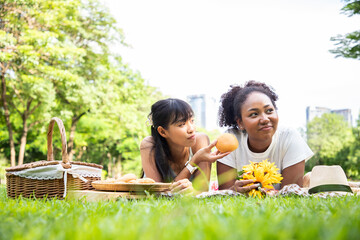 Couple LGBTQ women romance heartbreak emotions concept while picnic in the park. Angry girl rejects bread her girlfriend. Moody female upset on her dear.