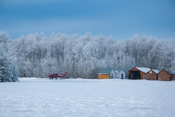 winter landscape frost on trees small plane on ground.  Private buildings northern canada
