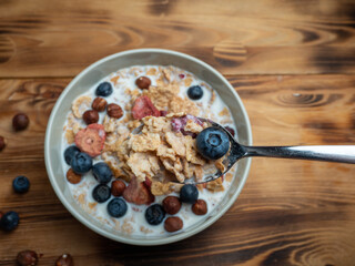 A cup with muesli and fresh berries on a wooden table. Healthy food, snack or breakfast.