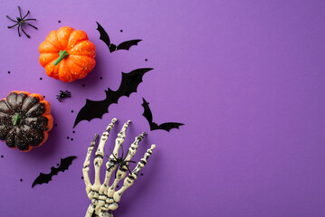 Halloween creepy decorations concept. Top view photo of skeleton hand pumpkins bat silhouettes spiders and confetti on isolated violet background - Powered by Adobe