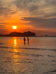 Fototapeta premium woman silhouette stay in sea water at orange sunset