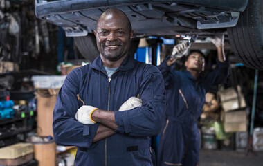 African male mechanic with armcrossed standing in auto repair shop, Car maintenance concept