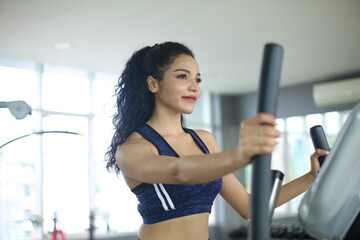 close-up shot of woman working out on elliptical machine at gym