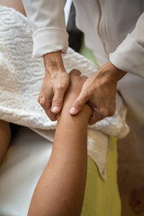 Detalhe de mãos de massagista, que está aplicando massagem terapêutica na mão de um paciente que está deitado. - obrazy, fototapety, plakaty
