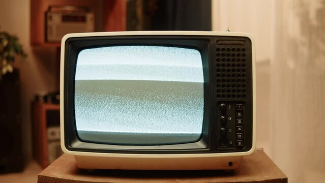 Old television with gray screen at home. Close-up of vintage tv in living room, nostalgia. Searching channel, bad signal. 