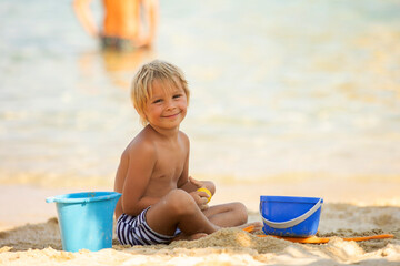 Happy child on the beach, playing in the sand, enjoying summer