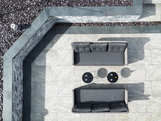 Aerial view overhead of a patio sofas and tables, with a bottle of wine and wine glasses. No people.