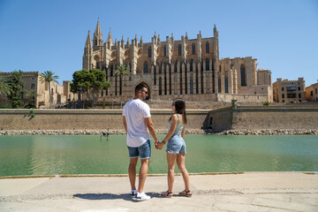 Couple in love gazing into each other's eyes with sunglasses and the famous cathedral of Palma de...