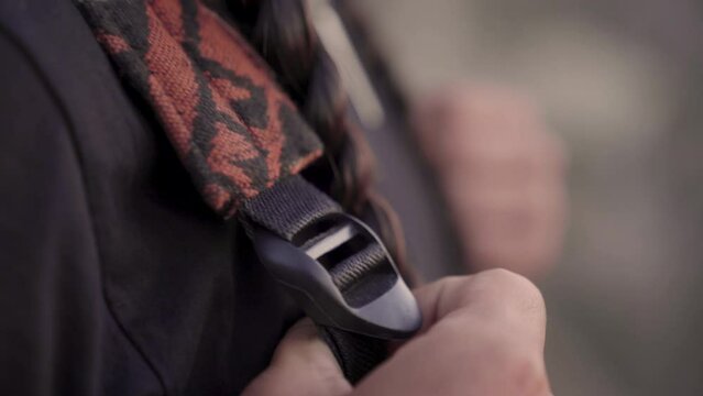 Very close up frame of a Native American man's hands grabbing his backpack straps.