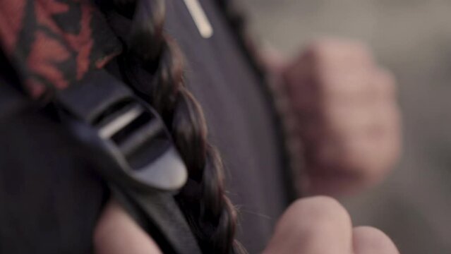 Young Native American man holds onto his backpack straps as he looks into the distance. 