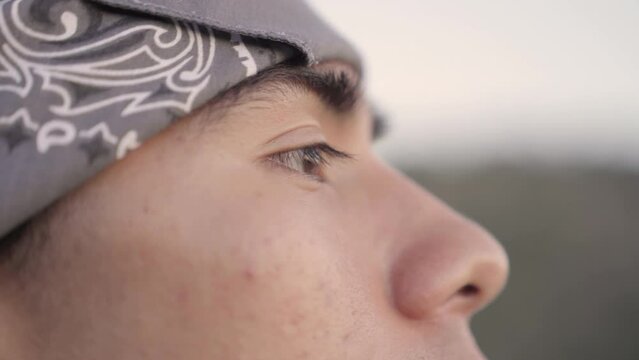 Very close up frame of a young Native American man's eyes as he looks into the distance in the outdoors.