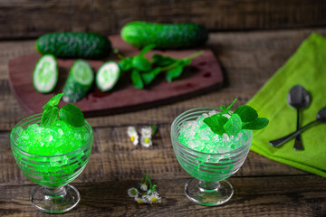 Summer Sicilian dessert granita, frozen juice of fresh cucumber and mint on a wooden background. Summer cooling, tonic cocktail of crushed ice, a kind of sherbet.