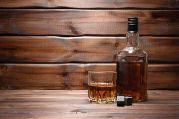  Whiskey in the drinking glass and bottle on the brown wooden table background with copy space. - obrazy, fototapety, plakaty