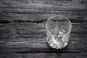 Empty drinking glass for whiskey on the black wooden table background with copy space.