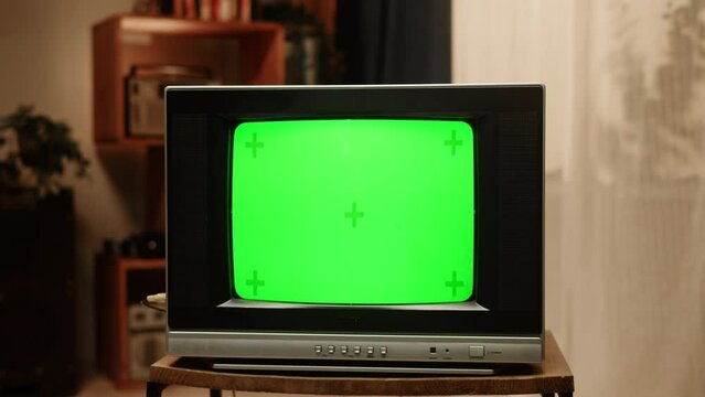 Old television with green chroma key screen at home. Close-up of vintage tv in living room, nostalgia.