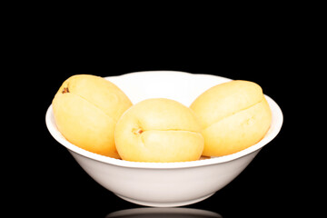 Three bright yellow juicy pineapple apricots in a pottery, macro, isolated on a black background.	