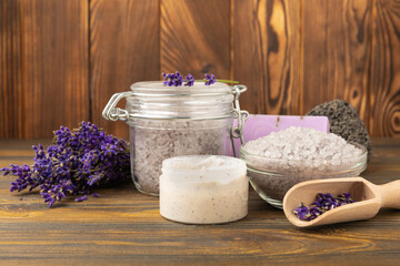 Lavender spa. Sea salt, lavender flowers, essential oils, body cream and handmade soap. Natural herbal cosmetics with lavender flowers on brown texture background. Relax and spa concept.Space for text