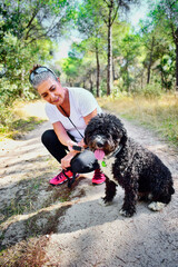 Mujer madura de pelo gris jugando con un perro negro en el campo.
