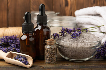 Fototapeta na wymiar Lavender spa. Sea salt, lavender flowers, essential oils, body cream and handmade soap. Natural herbal cosmetics with lavender flowers on brown texture background. Relax and spa concept.Space for text