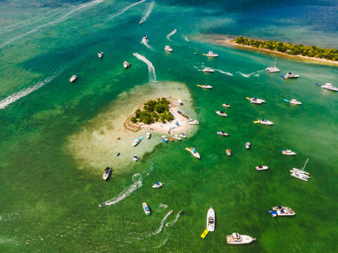 Yachts floating near islet in ocean on sunny day