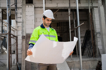 An engineer or technician with a helmet is planning on building blueprints on a construction site. Professional technicians at the construction site. Workers at a construction site.