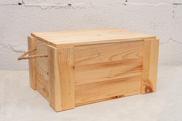 Wooden box made of planks with a rope handle for storing and transporting objects on a textured...