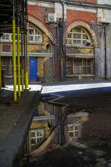 Fototapeta na wymiar Old brick railway archway buildings at Waterloo reflected in puddle on road