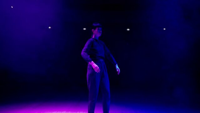 fabulous dance show on theatre stage with artistic blue and pink lights, woman is dancing like robot