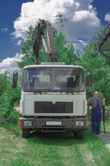Obraz premium Unloading paving slabs from a truck. Men unload paving slabs using a manipulator. Workers unload building materials from a large machine.